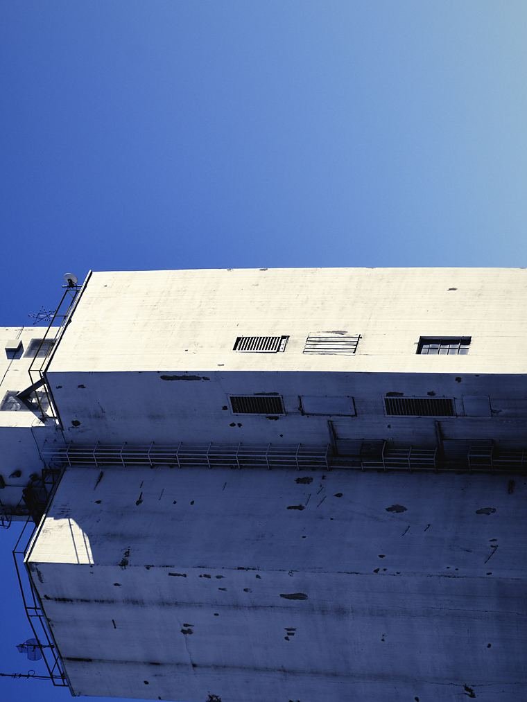 Concrete grain storage silos seen from below against an open sky